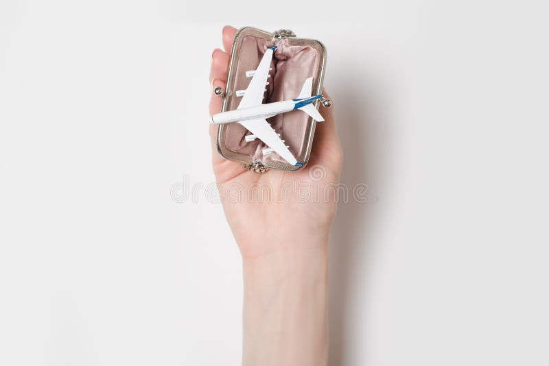 Passenger plane in the wallet on the female palm on a light background. Cheap flights.