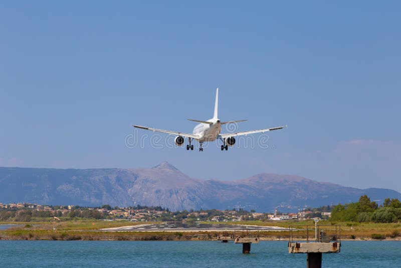 Passenger`s airplane is landing at Kerkyra Airport. Greece, Corfu island. Decrease in height, close-up. Runway on the background of mountains and sea. Airplane height stock images, royalty-free photos and pictures