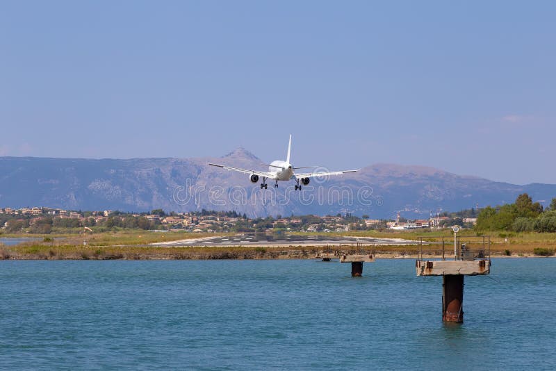Passenger`s airplane is landing at Kerkyra Airport. Greece, Corfu island. Decrease in height, close-up. Runway on the background of mountains and sea. Airplane height stock images, royalty-free photos and pictures