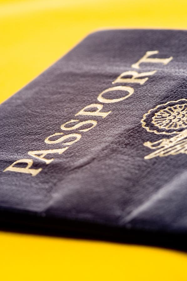 An American or United States passport on a yellow background with a shallow depth of field. An American or United States passport on a yellow background with a shallow depth of field