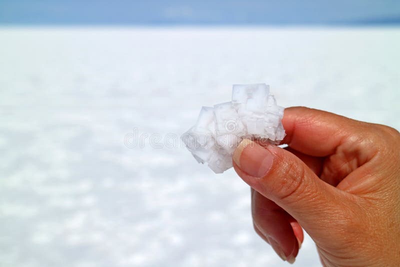 Passi la tenuta dei cristalli naturali bianchi puri del sale con Salar de Uyuni Salt Flats vago della Bolivia nel fondo immagine stock Passi la tenuta dei cristalli naturali bianchi puri del sale con Salar de Uyuni Salt Flats vago della Bolivia nel fondo immagine stock
