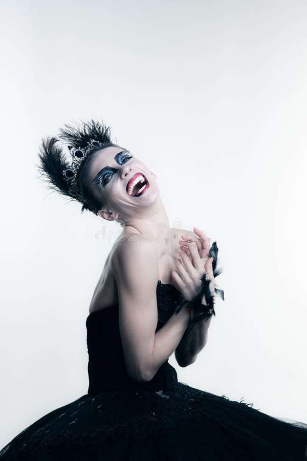 Portrait of young ballerina wearing black tutu, stage dress and bright make-up posing  on white studio