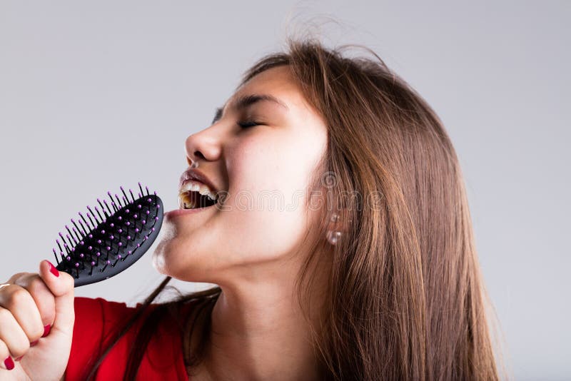 Passionate beautiful woman pretending to sing using her hairbrush. Passionate beautiful woman pretending to sing using her hairbrush