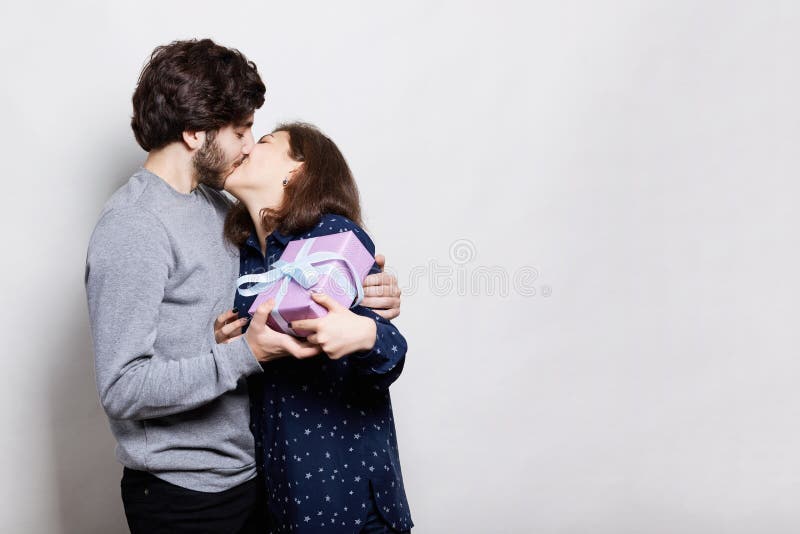 A passionate kiss of young couple. A happy woman kissing her boyfriend being happy and thankful to receive a present from him. Lo