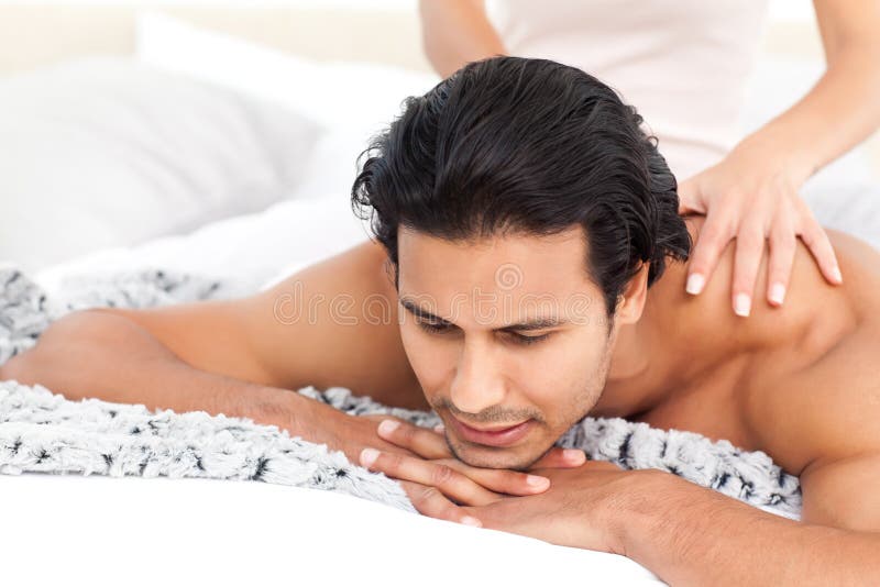 Passionate woman doing a massage to her boyfriend lying on their bed at home