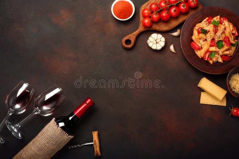 Pasta with cheese, cherry tomato sauce, wineglass and bottle wine, corkscrew, garlic, turmeric on rusty background