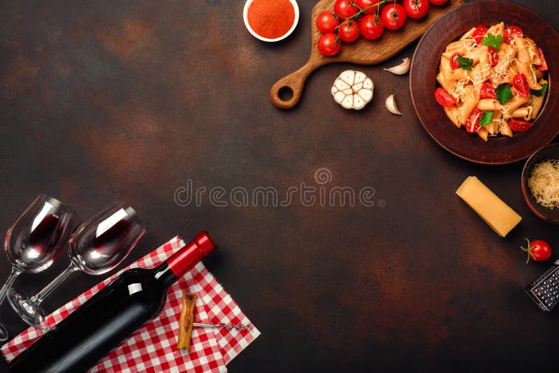 Pasta with cheese, cherry tomato sauce, wineglass and bottle wine, garlic, turmeric on rusty background