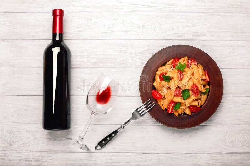 Pasta with cheese, cherry tomato , wineglass and bottle wine on white wooden boards