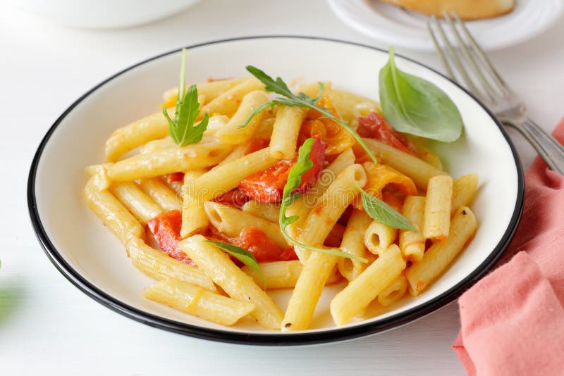 A delicious plate of penne pasta coated in a thick red tomato sauce and topped with melted white cheese.