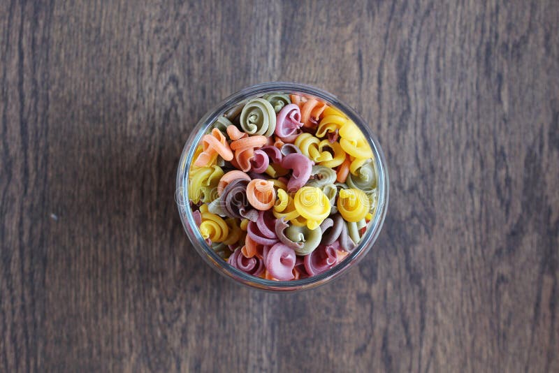 Pasta colorata in una latta sulla tavola di legno immagine stock Pasta colorata in una latta sulla tavola di legno immagine stock