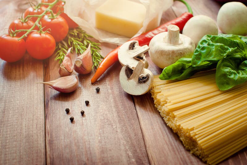 Pasta cruda, pomodori, funghi ed altri prodotti sul fondo di legno della tavola, vista superiore fotografia stock Pasta cruda, pomodori, funghi ed altri prodotti sul fondo di legno della tavola, vista superiore fotografia stock