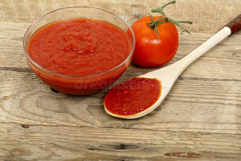 Bowl of tomato paste on wooden surface. Bowl of tomato paste on wooden surface