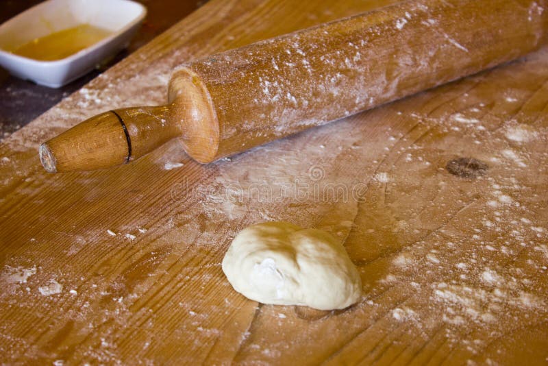 Pasta di lievito in farina su un bordo di legno con il matterello fotografia stock Pasta di lievito in farina su un bordo di legno con il matterello fotografia stock