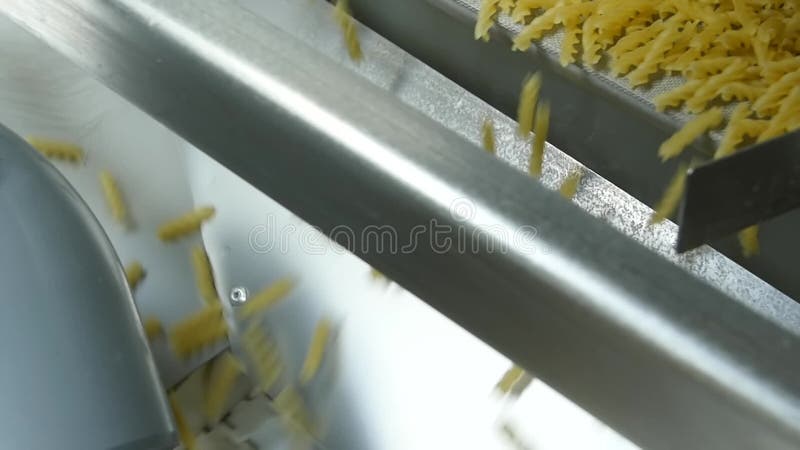 Pasta factory and pasta production stages. Close up of dry macaroni spilling from machine unit on modern food production