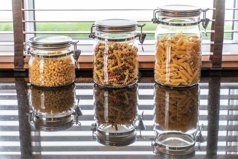 Pasta Fusilli and Macaroni in Glass Bottle in Kitchen Stock Photo