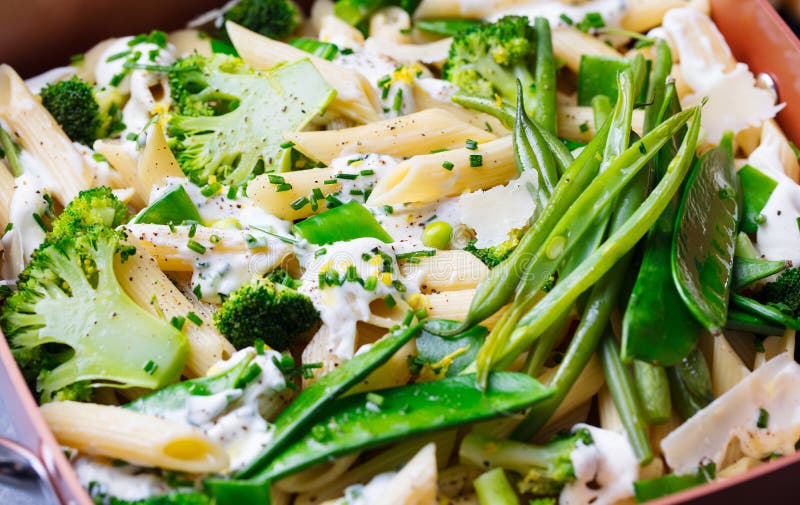 Pasta with green vegetables and creamy sauce in black bowl on grey stone background. Close up. royalty free stock photography Pasta with green vegetables and creamy sauce in black bowl on grey stone background. Close up. royalty free stock photography