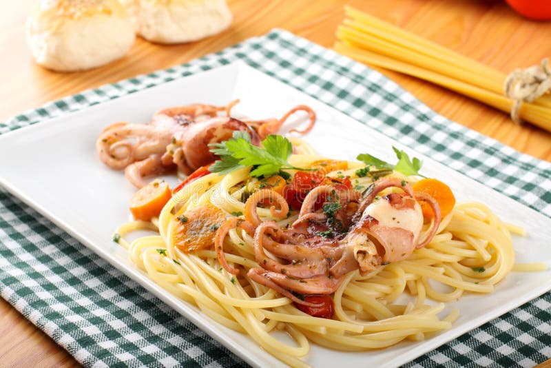 Pasta with octopus, tomatoes and carrots royalty free stock image