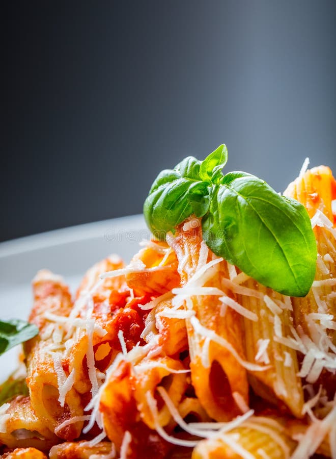 Pasta Penne with Tomato Bolognese Sauce, Parmesan Cheese and Basil on a Fork. Mediterranean food.Italian cuisine