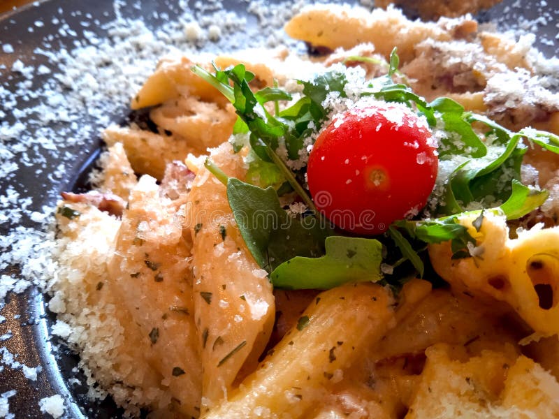 Pasta plate top view, macaroni with cherry tomato, salad and parmesan cheese. Close up food photo