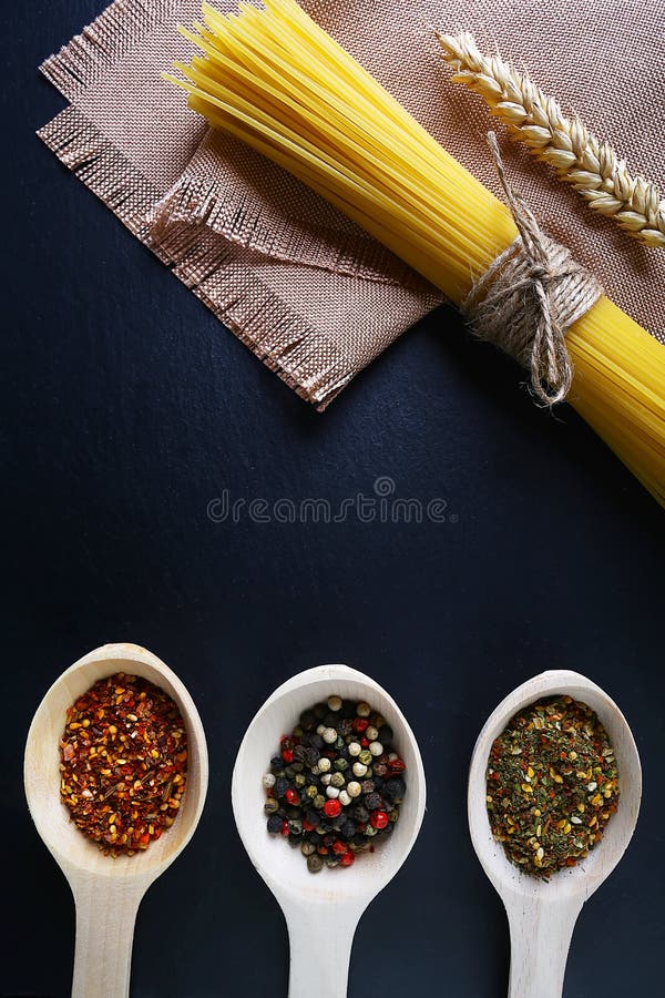 Pasta spaghetti, wheat spikes, on a napkin, wooden spoons with spices, background of food ingredients, image of the concept of adv royalty free stock images Pasta spaghetti, wheat spikes, on a napkin, wooden spoons with spices, background of food ingredients, image of the concept of adv royalty free stock images