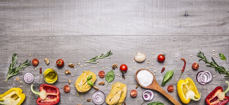 Pasta, tomatoes and ingredients for cooking on rustic background, top view, border. Italian food concept