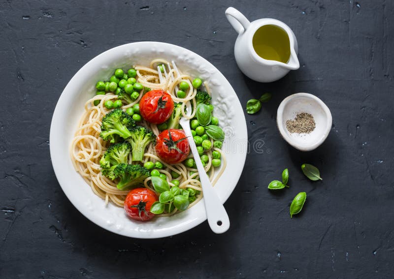 Pastas del Veggie Almuerzo vegetariano - espagueti con la col del bróculi, los guisantes verdes y los tomates de cereza en el fon imagenes de archivo Pastas del Veggie Almuerzo vegetariano - espagueti con la col del bróculi, los guisantes verdes y los tomates de cereza en el fon imagenes de archivo