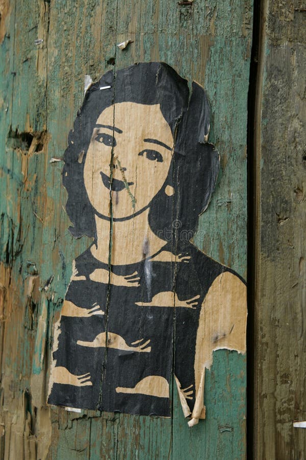 Small paste up drawing of a woman with dark hair, on a green painted lamp post in Vancouver. Small paste up drawing of a woman with dark hair, on a green painted lamp post in Vancouver