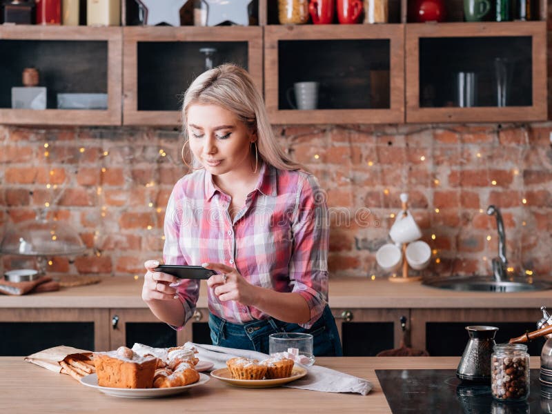 Food blogging hobby. Sweet homemade bakery assortment. Woman with smartphone shooting fresh cakes and pastries. Food blogging hobby. Sweet homemade bakery assortment. Woman with smartphone shooting fresh cakes and pastries.