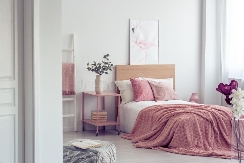 Pastelkleur roze hoofdkussen en deken op enig houten bed met wit beddegoed in Skandinavisch slaapkamerbinnenland