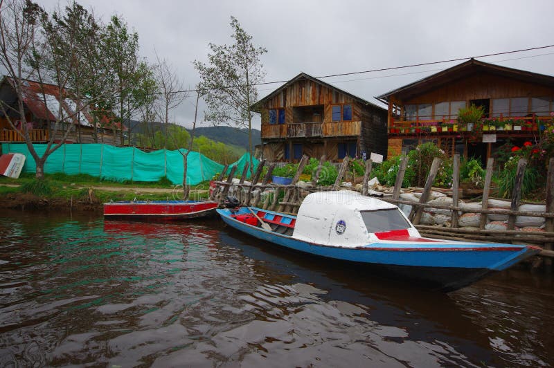 PASTO, COLOMBIA - JULY 3, 2016: small boats parked next to a shore with some wood houses as background