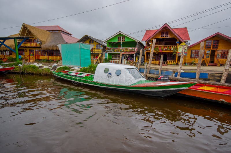 PASTO, COLOMBIA - JULY 3, 2016: small green boat parked next to an orange boat with some shops as background