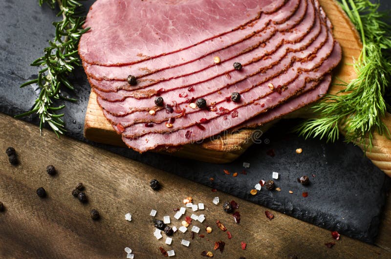 Pastrami coupée en tranches fraîche de boeuf entourée par des herbes dans le choppin en bois photos stock Pastrami coupée en tranches fraîche de boeuf entourée par des herbes dans le choppin en bois photos stock