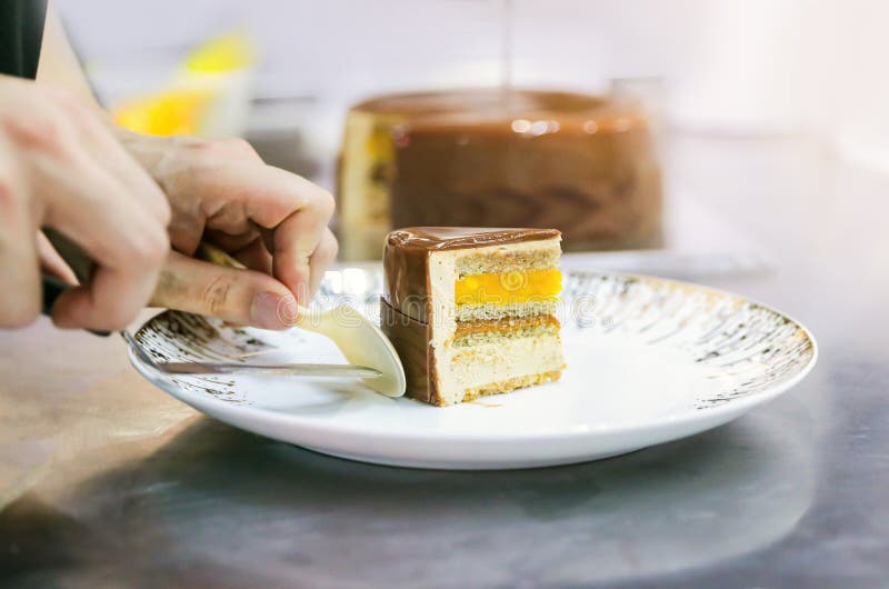 Pastry Chef Hand with Decorating Cake, Chef Cutting Homemade Chocolate Cake in Kitchen Stock
