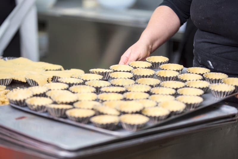 Pastry Chef Making Tartlets, Putting the Dough in Baking Dishes, at