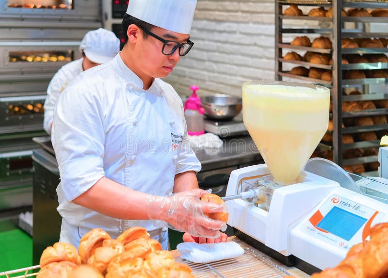 Pastryman putting cream into puffs in shopping mall in Busan stock photo Pastryman putting cream into puffs in shopping mall in Busan stock photo