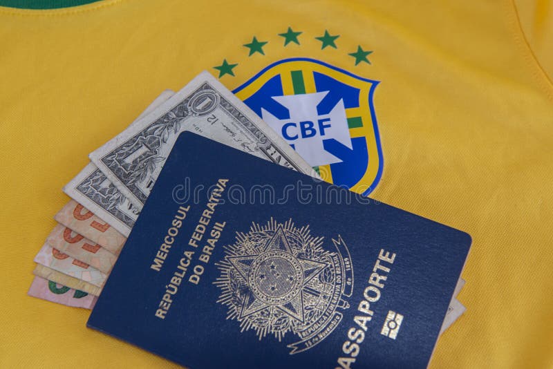 Bauru, Brazil - 11.01.23: Brazilian Football Confederation emblem on football jersey. Soccer players sale and trading concept. Passport and money from fans or players on the Brazilian team t-shirt. Bauru, Brazil - 11.01.23: Brazilian Football Confederation emblem on football jersey. Soccer players sale and trading concept. Passport and money from fans or players on the Brazilian team t-shirt