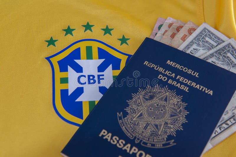 Bauru, Brazil - 11.01.23: Brazilian Football Confederation emblem on football jersey. Soccer players sale and trading concept. Passport and money from fans or players on the Brazilian team t-shirt. Bauru, Brazil - 11.01.23: Brazilian Football Confederation emblem on football jersey. Soccer players sale and trading concept. Passport and money from fans or players on the Brazilian team t-shirt