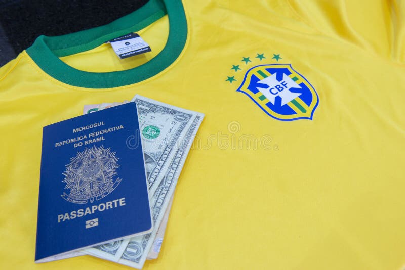 Bauru, Brazil - 11.01.23: Brazilian Football Confederation emblem on football jersey. Soccer players sale and trading concept. Passport and money from fans or players on the Brazilian team t-shirt. Bauru, Brazil - 11.01.23: Brazilian Football Confederation emblem on football jersey. Soccer players sale and trading concept. Passport and money from fans or players on the Brazilian team t-shirt