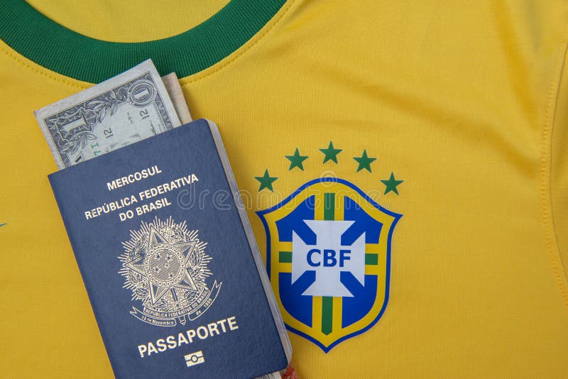 Bauru, Brazil - 11.01.23: Brazilian Football Confederation emblem on football jersey. Soccer players sale and trading concept. Passport and money from fans or players on the Brazilian team t-shirt. Bauru, Brazil - 11.01.23: Brazilian Football Confederation emblem on football jersey. Soccer players sale and trading concept. Passport and money from fans or players on the Brazilian team t-shirt