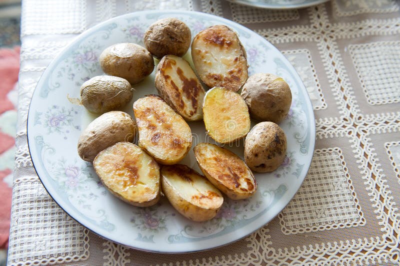 Patate al forno russe tradizionali con la buccia con olio vegetale su un piatto con un ornamento grigio fotografia stock Patate al forno russe tradizionali con la buccia con olio vegetale su un piatto con un ornamento grigio fotografia stock
