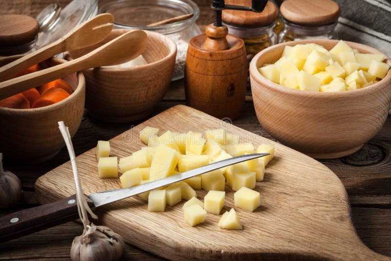 Patate tagliate su un tagliere di legno immagini stock libere da diritti Patate tagliate su un tagliere di legno immagini stock libere da diritti