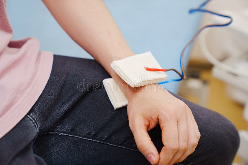 Patient with an Electrotherapy on Hand. Electrical Stimulation. Stock