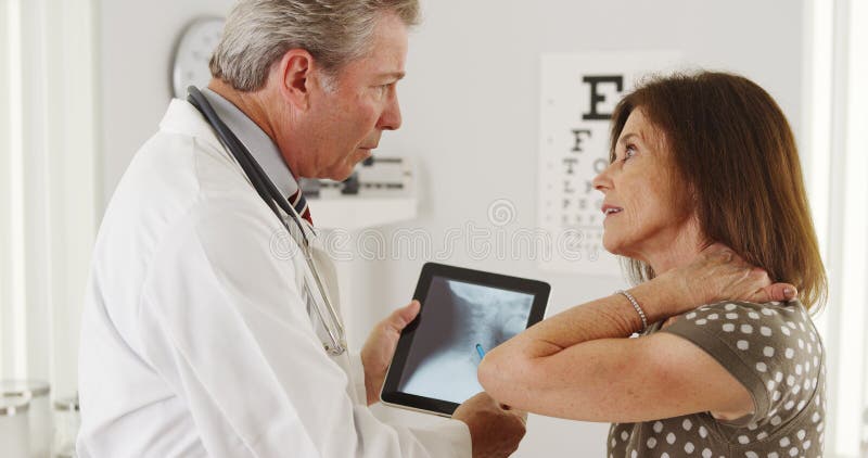 Patient explaining neck problems to senior doctor stock photos