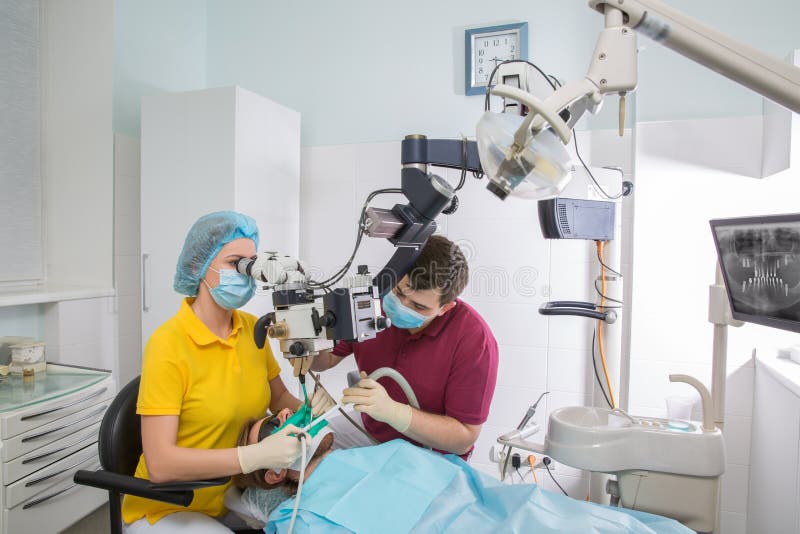 Patient professionnel d'examen de dentiste avec le microscope au bureau photo libre de droits Patient professionnel d'examen de dentiste avec le microscope au bureau photo libre de droits