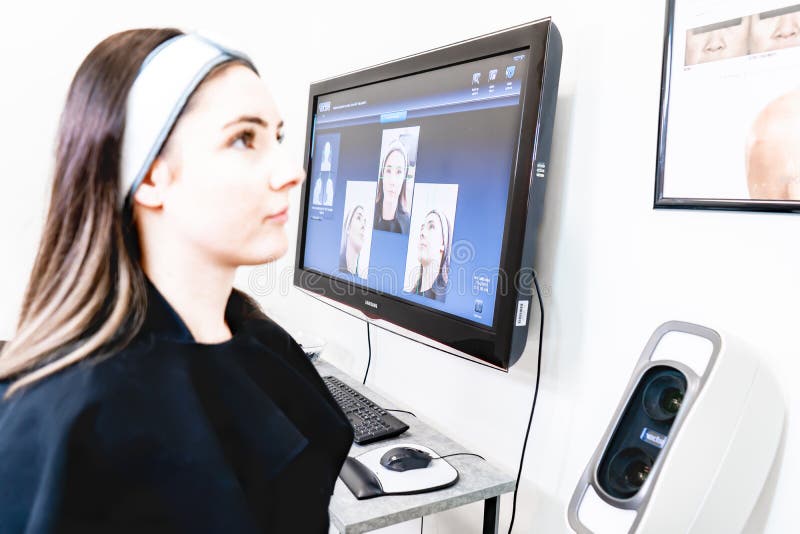 Patient sitting for Vectra 3D imaging scan, in a beauty laser clinic, for tracking procedure results with digital analysis.
