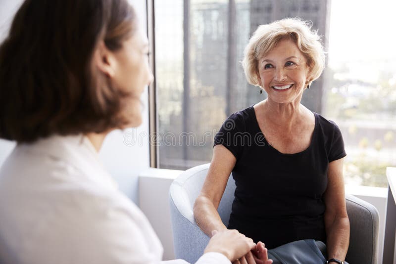 Patiente supérieure féminine de femme de docteur In Office Reassuring et tenir ses mains images libres de droits Patiente supérieure féminine de femme de docteur In Office Reassuring et tenir ses mains images libres de droits