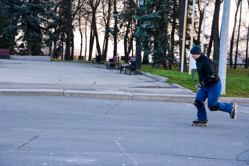 Patinagem de rolo do homem da atividade de lazer na central da cidade no por do sol Inverno foto de stock Patinagem de rolo do homem da atividade de lazer na central da cidade no por do sol Inverno foto de stock