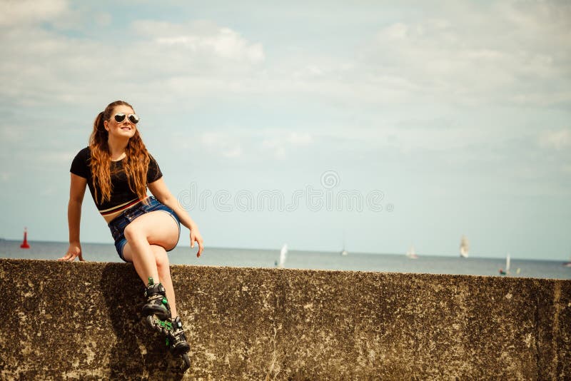 Patins de rolo vestindo da jovem mulher feliz imagem de stock royalty free Patins de rolo vestindo da jovem mulher feliz imagem de stock royalty free