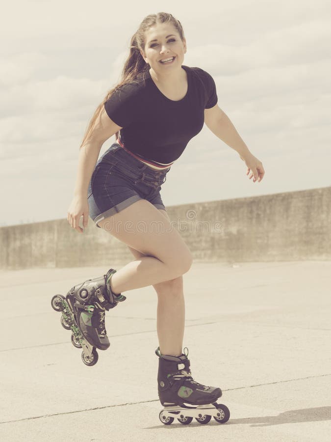 Patins de rolo vestindo da jovem mulher feliz imagens de stock royalty free Patins de rolo vestindo da jovem mulher feliz imagens de stock royalty free