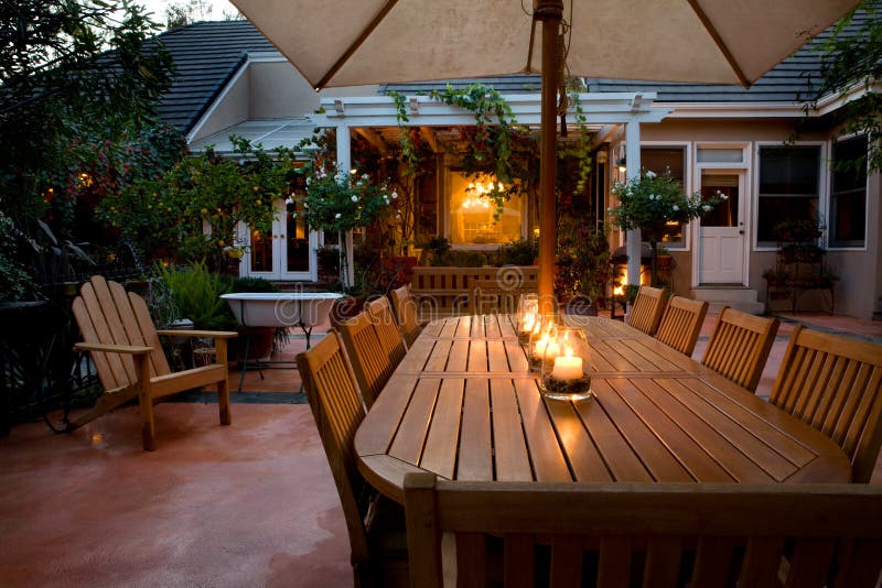 In vista di un confortevole a lume di candela, tavolo e sedie in legno su un patio all'aperto al tramonto.